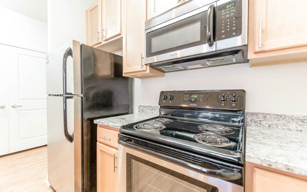 A view of the counter, cabinets, refrigerator, and stove in the kitchen of an apartment at 101 E. Corry
