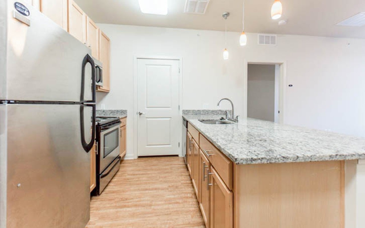 A view of the counter, cabinets, refrigerator, and stove in the kitchen of an apartment at 101 E. Corry