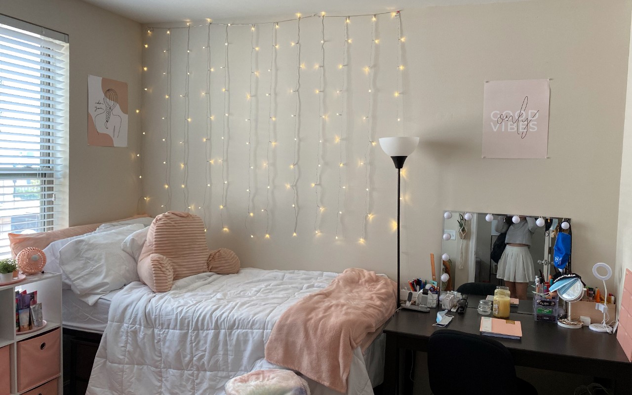 Twin bed located against window with decorations along the side of the wall. A desk sits at the foot of the bed.
