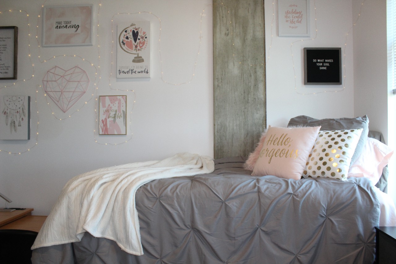 A twin bed rests against the wall in a double room. Decorations line the wall it sits against and the head of the bed is against a window.
