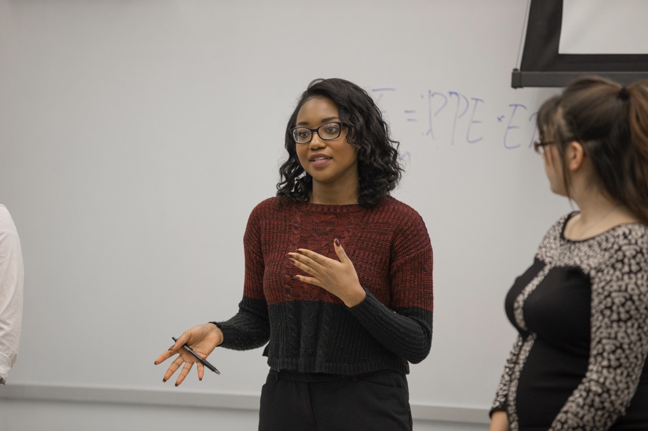 Student presenting in front of a white board