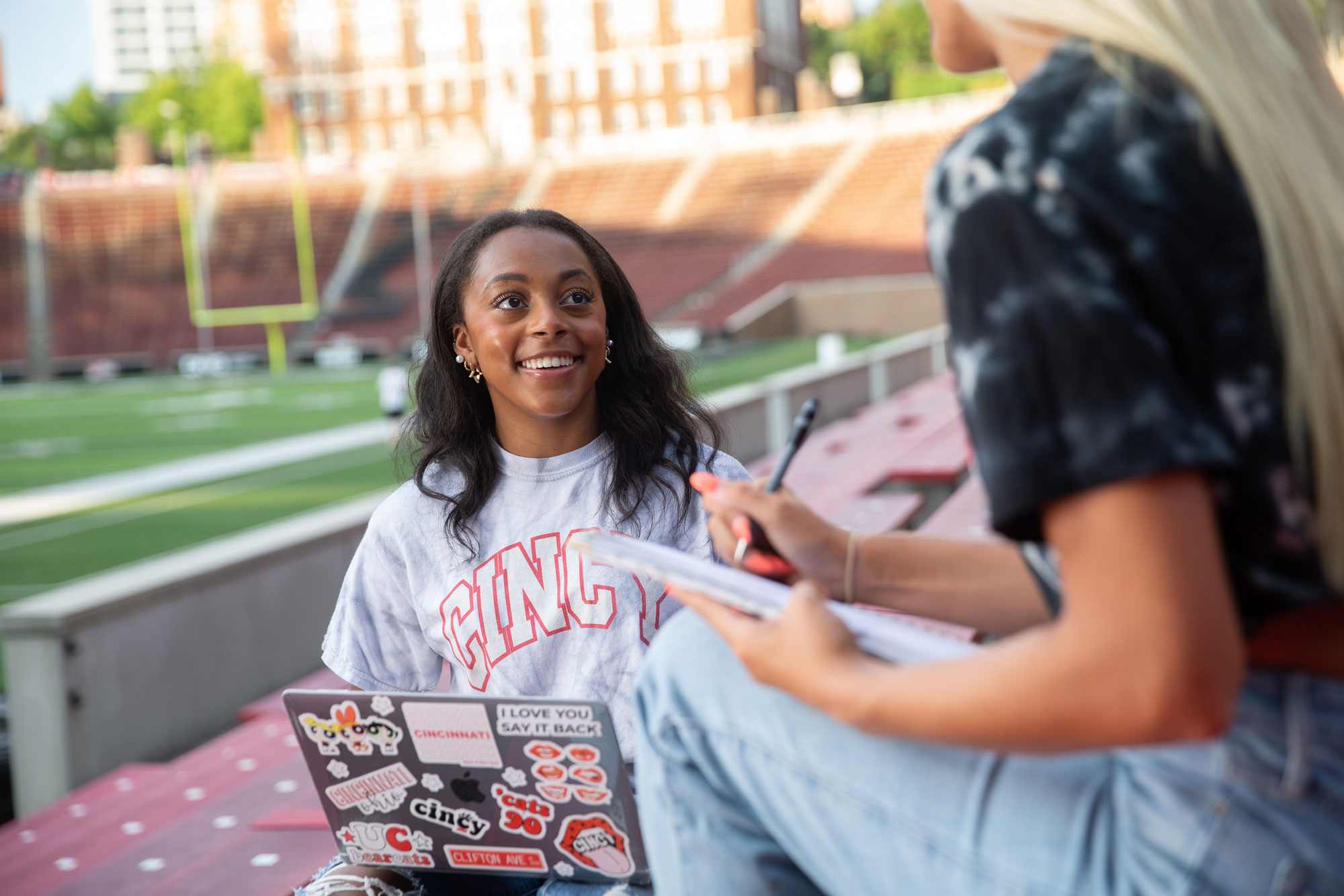 Two University of Cincinnati students laugh as they sit in UC's Nippert Stadium