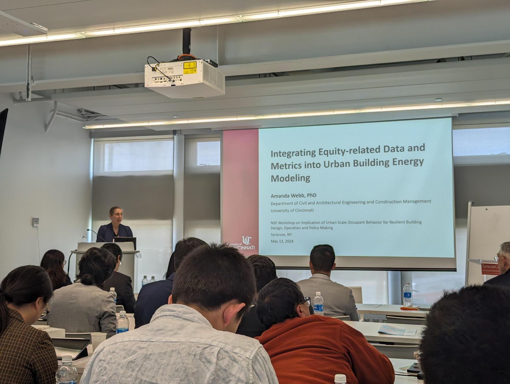 Amanda Webb stands at a podium and presents to a group of people. 