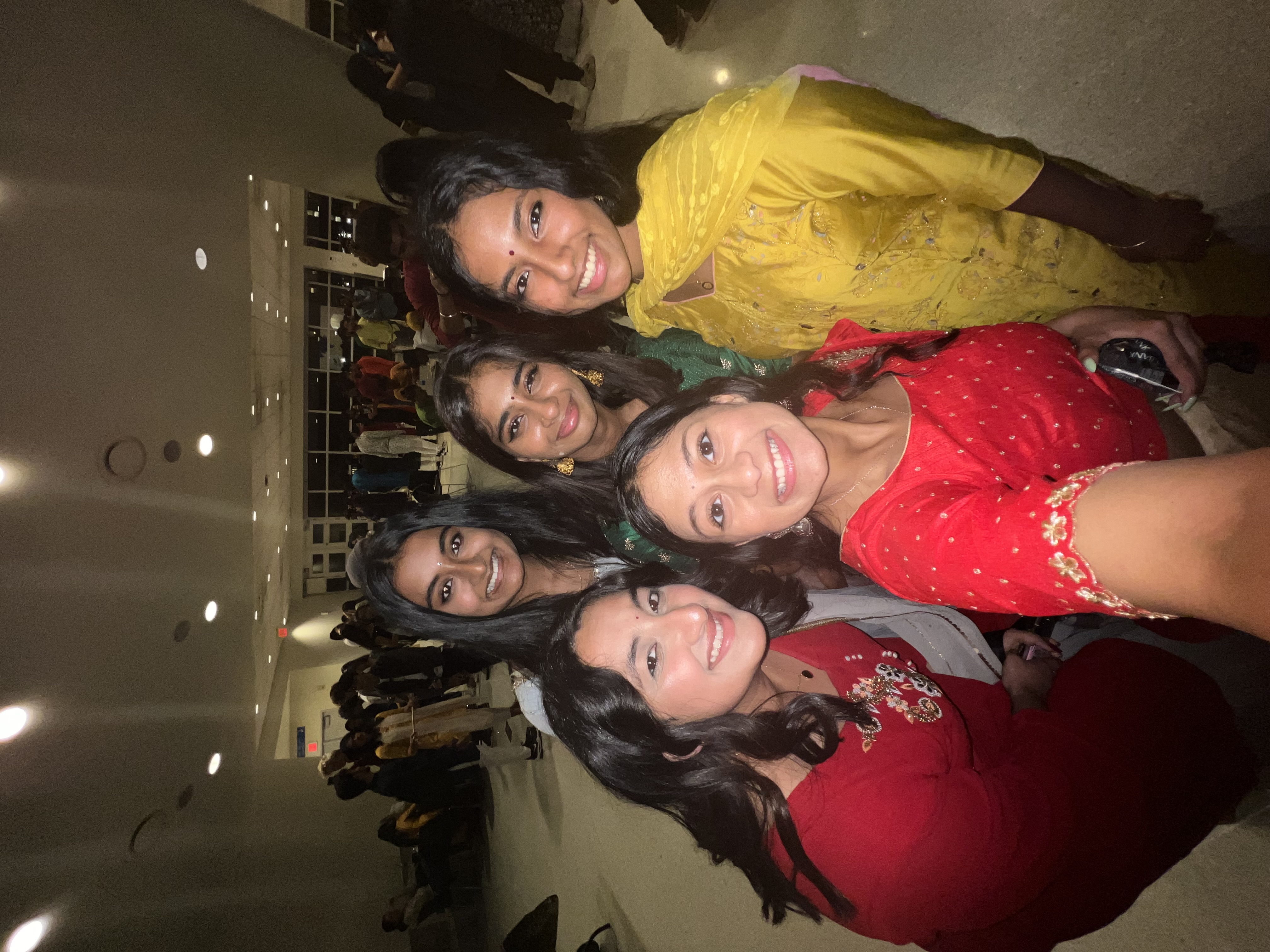 five girls in colorful dresses smile and take a selfie