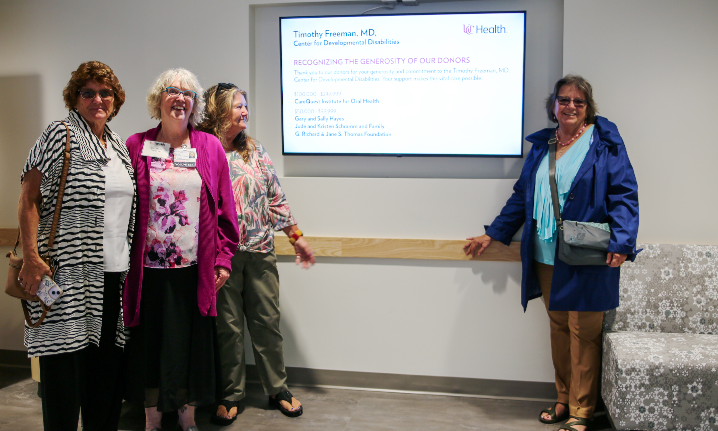 Donors stand inside a new medical clinic near virtual signage.