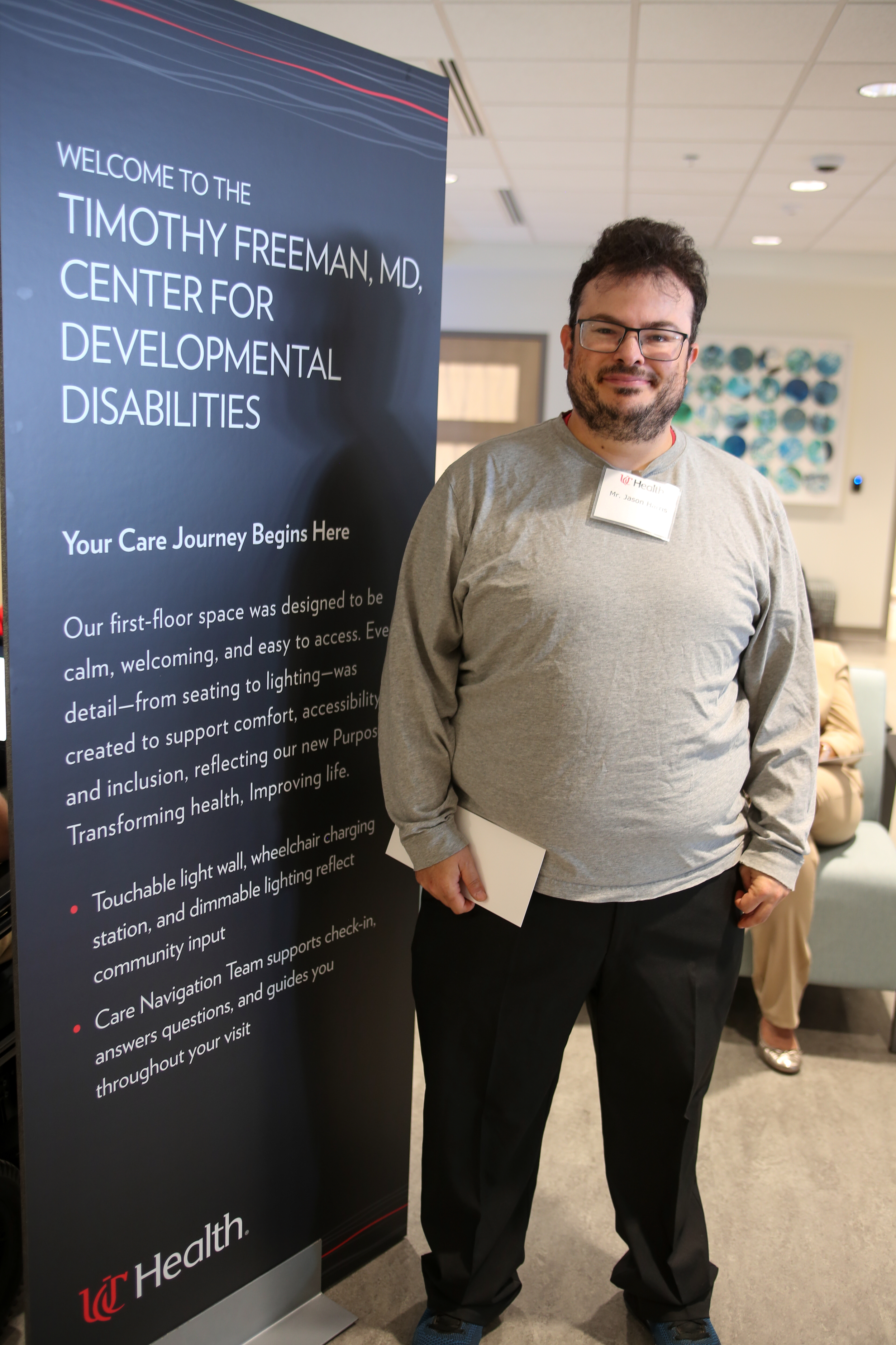Man stands beside a large sign welcoming people to the new Freeman Center in Cincinnati.