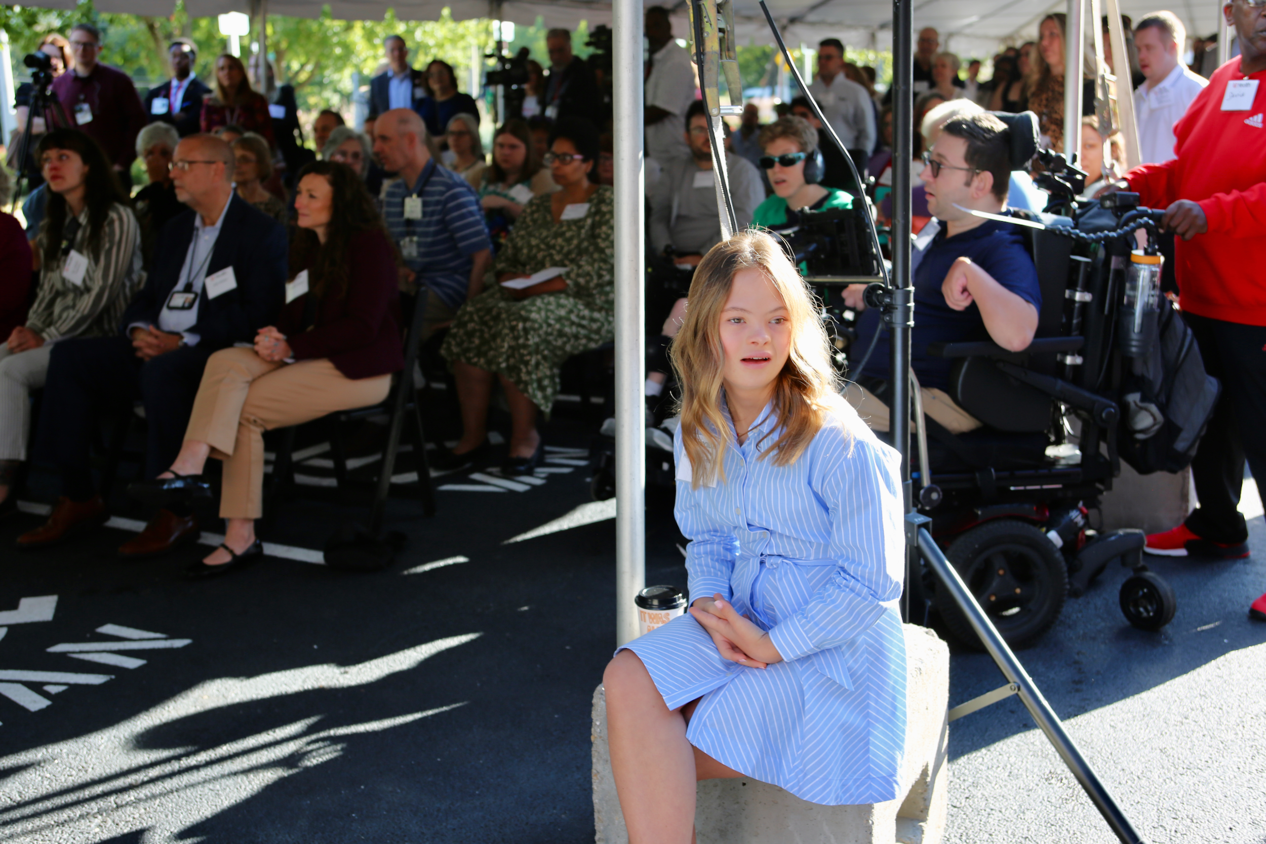 Young woman sits with several people in front of a new medical clinic.