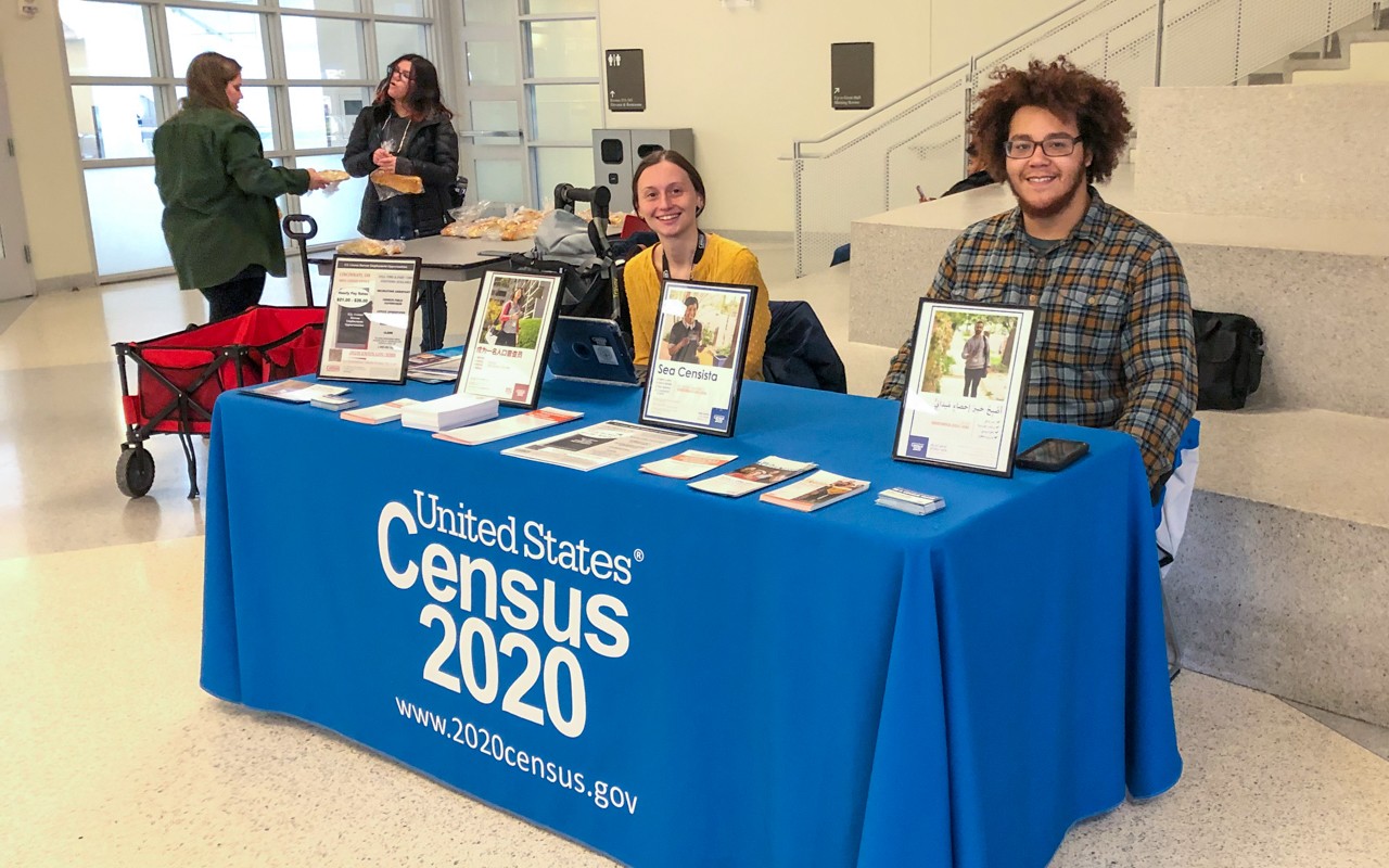 Two young workers at a table offering census information