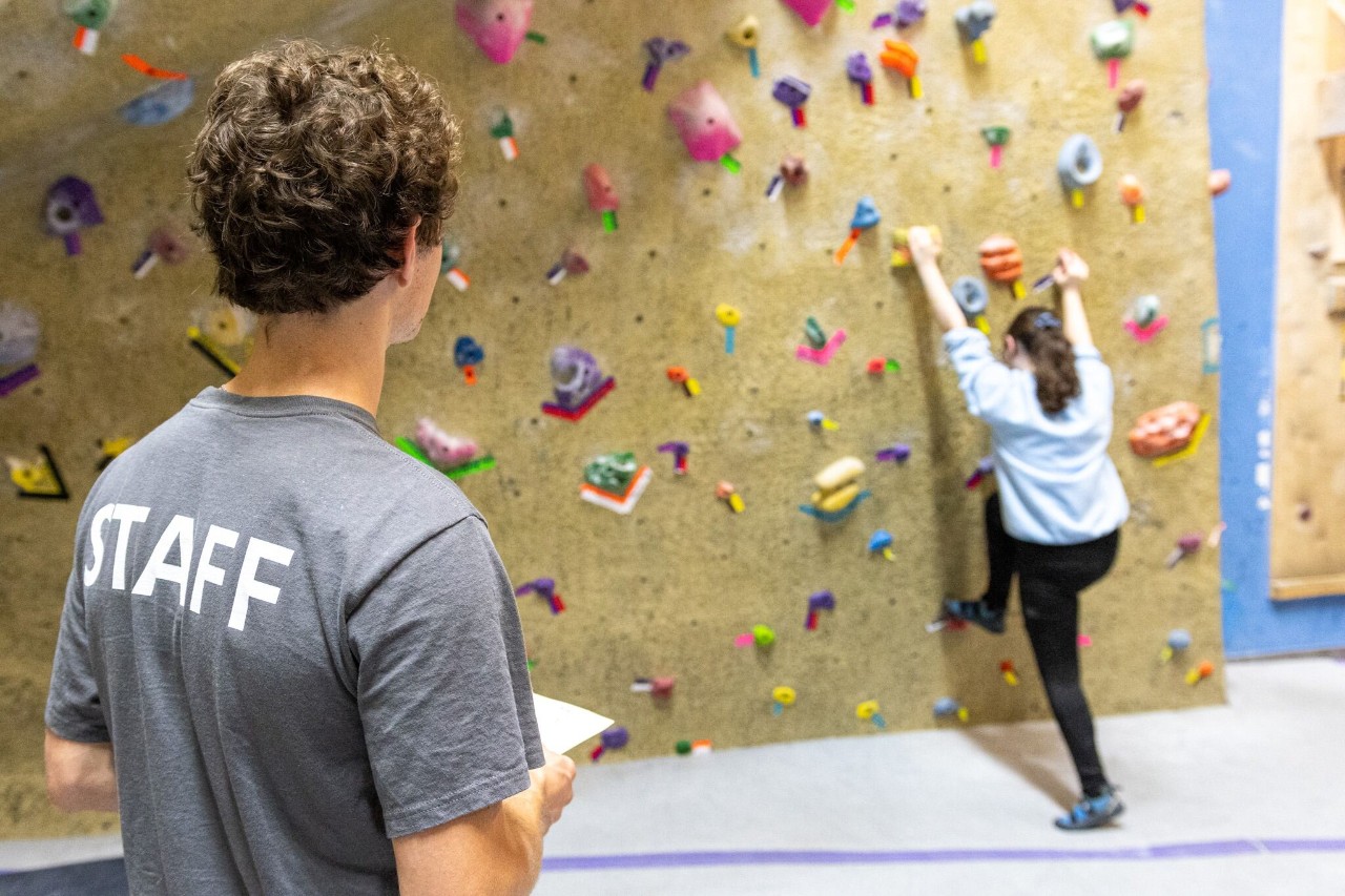 A Campus Recreation guest climbs on the climbing wall.