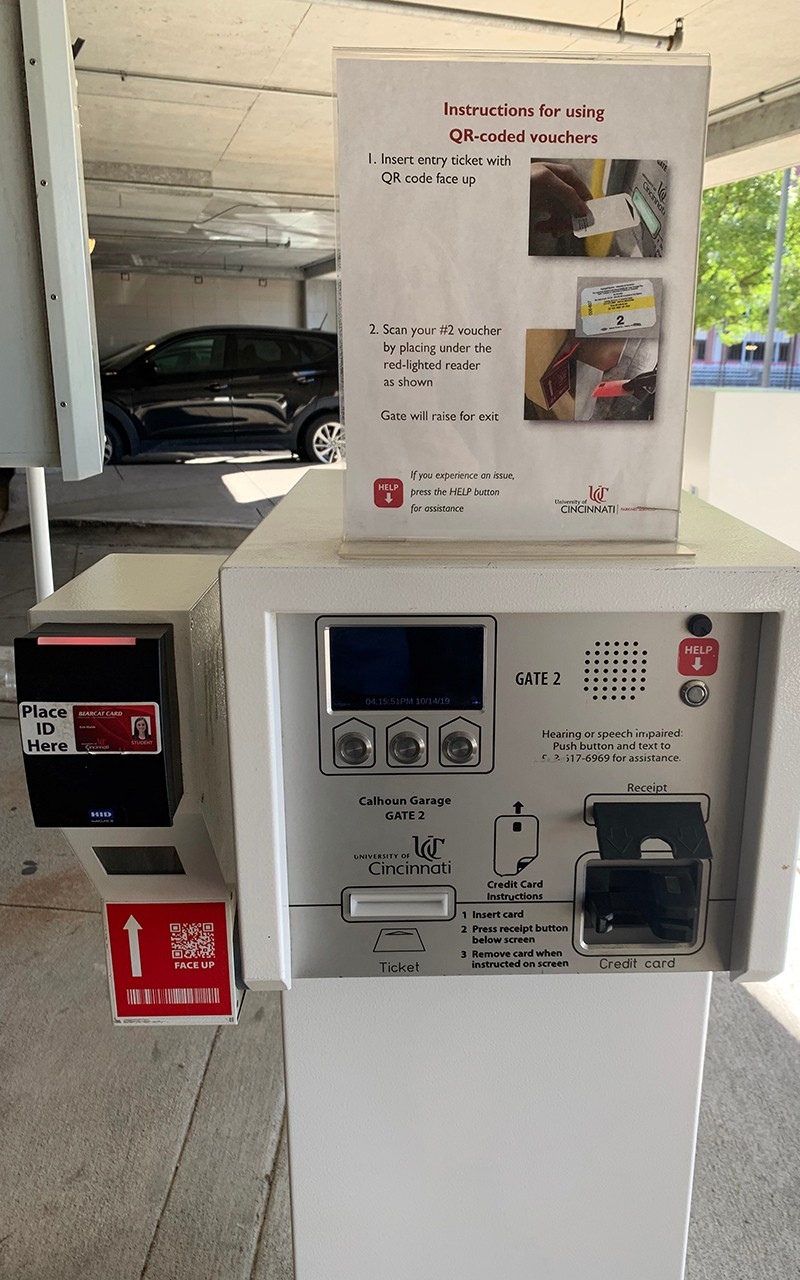 An exit machine for parking. There on instructions at the top of the machine, and the machine has decals indicating scan tool, credit card payment and help button for assistance