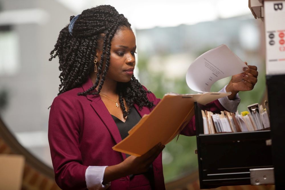 young woman in suit looks at files from a filing cabinet
