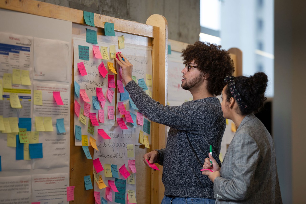 Students at a board placing sticky notes