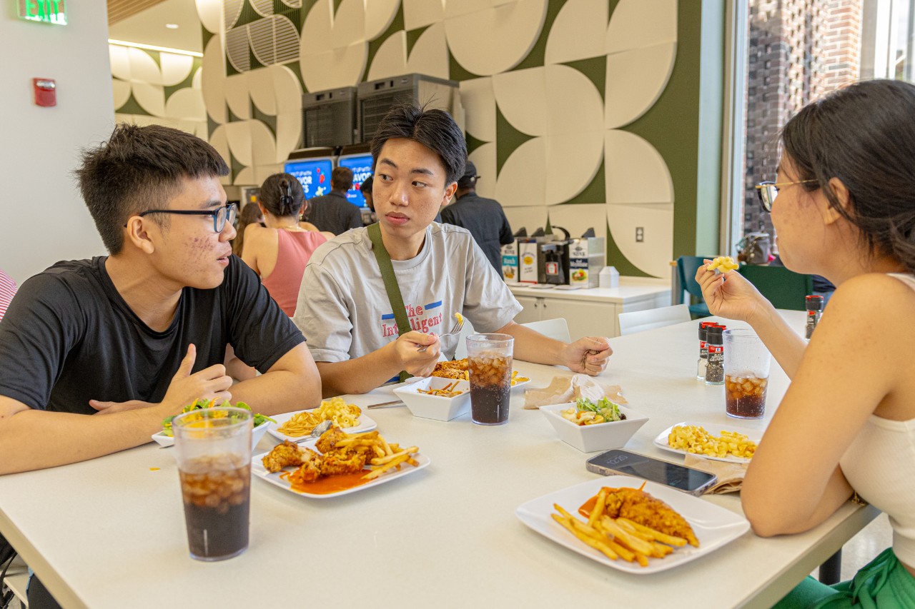 Students eat and chat at a table in the dining center.