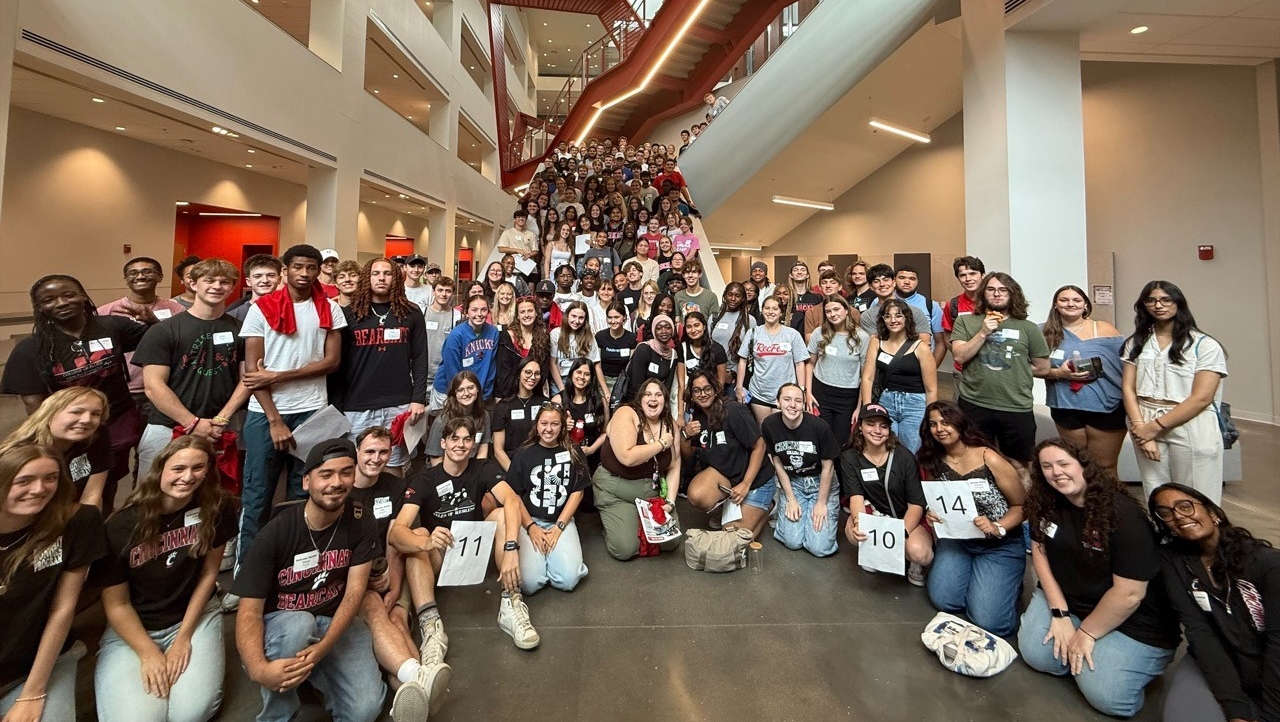 A large group of students gathered smiling for a photo in Clifton Court Hall 