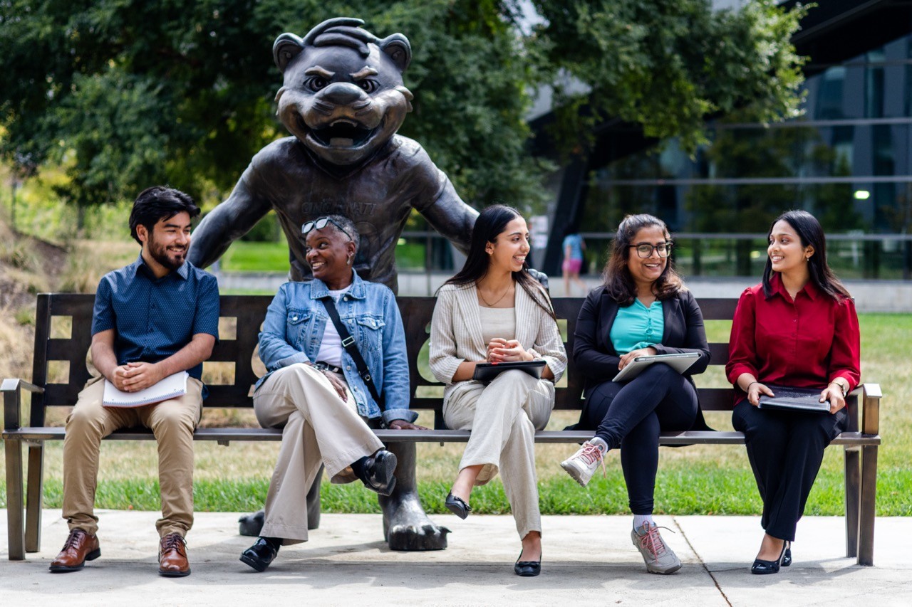 Students sitting on the Bearcat Bench smiling and talking