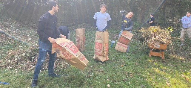 Students standing outside with yard waste bags on a sunny fall day
