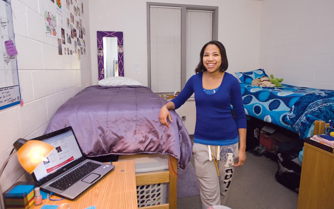 Student standing next to standard loft bed in standard double room in Turner Hall.