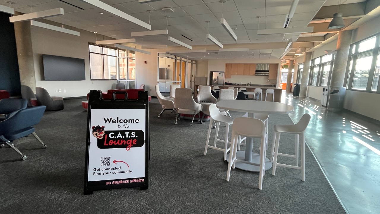 A large room lit with sunlight coming in from the windows. The room is filled with furniture, including lounge chairs and tables. A sign reads Welcome to the C.A.T.S. Lounge.
