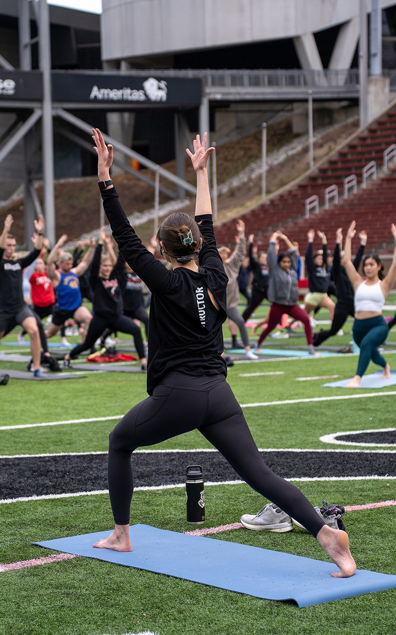 yoga class in nippert stadium with students and instructor in high lunge pose