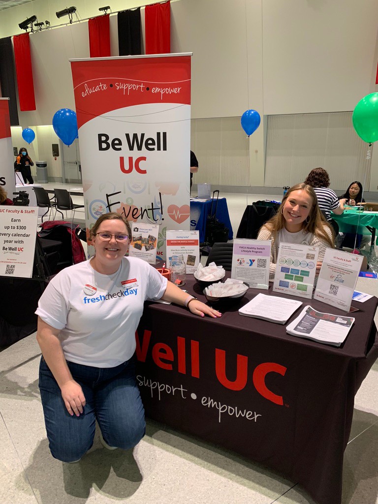 staff and student volunteering at Be Well UC table during Fresh Check Day