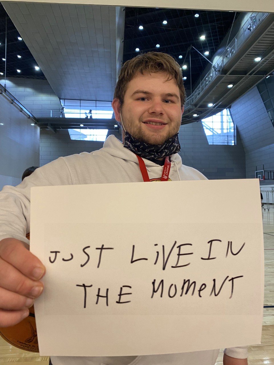 Male student holding up a sign that says "just live in the moment"