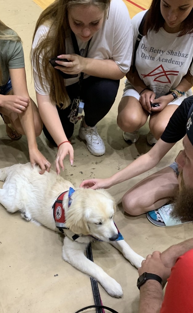 Students surrounding 4-Paws puppy