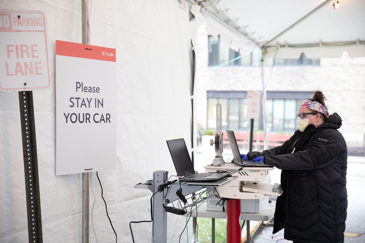A first responder wearing a facemask stands at a workstation in a COVID-19 drive thru testing facility