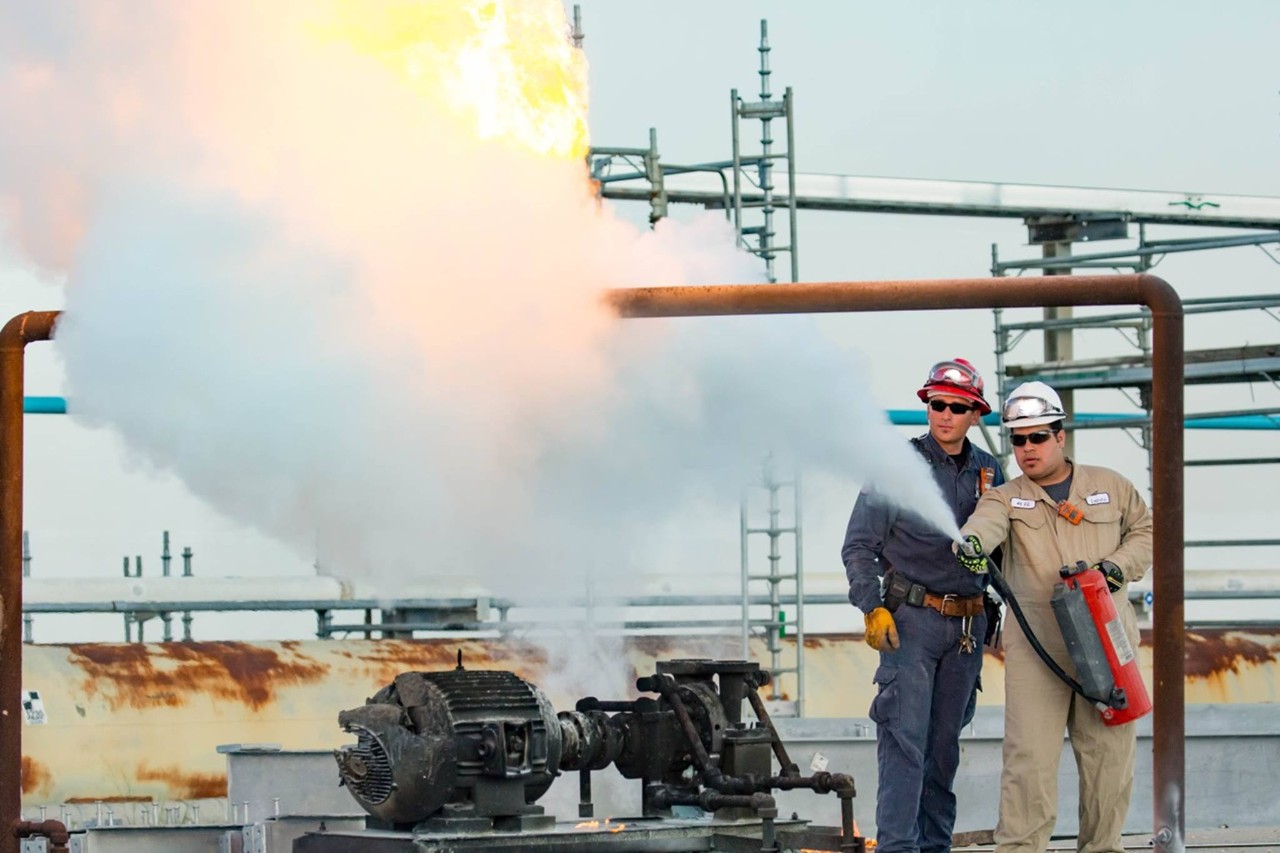 Elgafy and supervisor at a refinery using a fire extinguisher to put out a fire. 