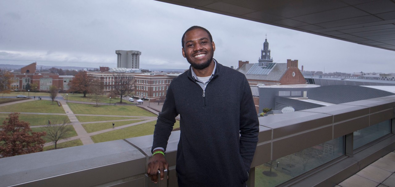 Serge Kikonda stands on 6th floor balcony in UC's Pavilion building.