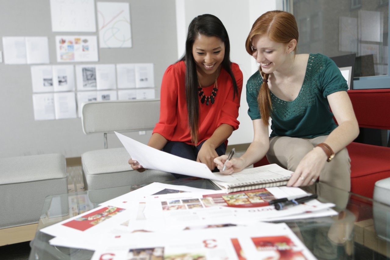 Two women look over a booklet together