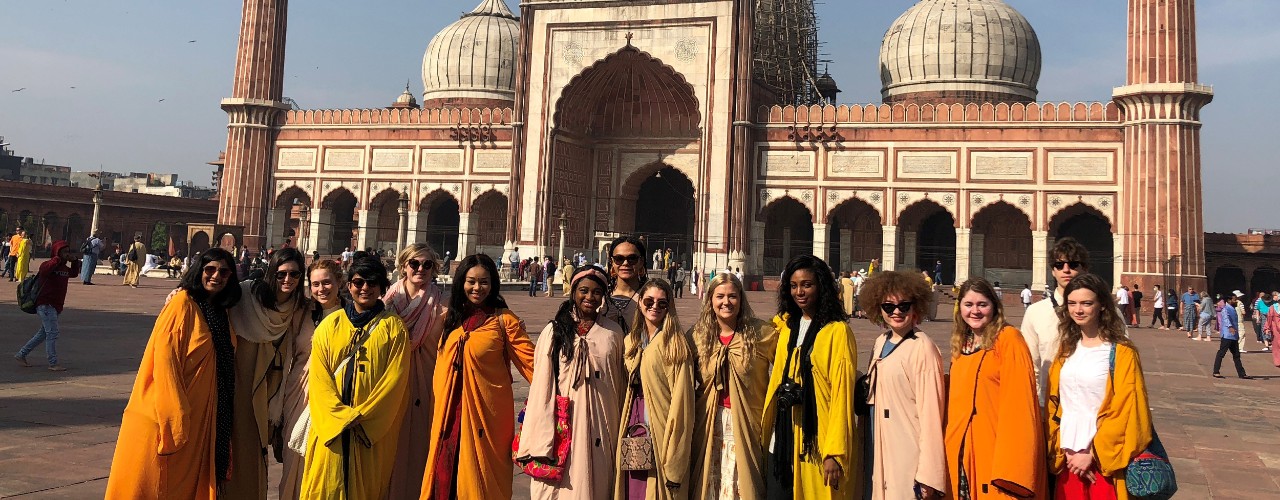 Students stand in front of a temple in India.
