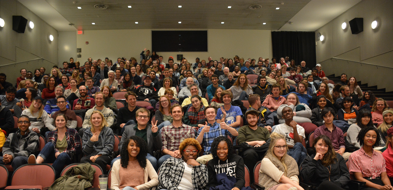 A group of people gather in a movie theater to watch a film