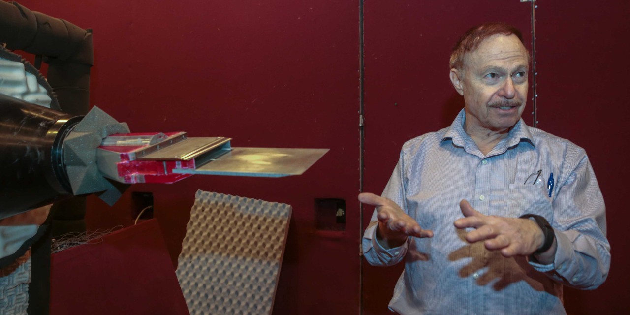 Ephraim Gutmark stands in front of a jet engine in a soundproof UC lab.