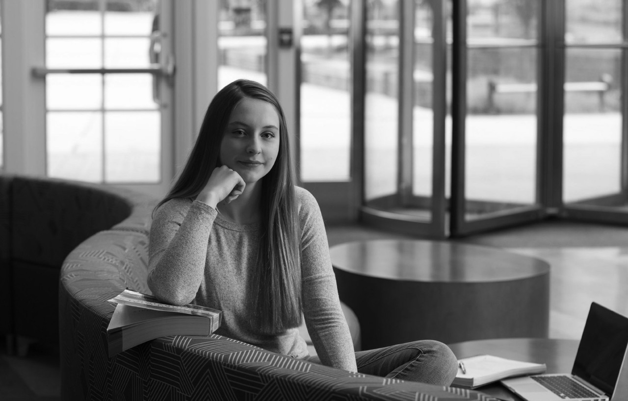 Woman posing with her chin resting on her hand on a couch in an atrium