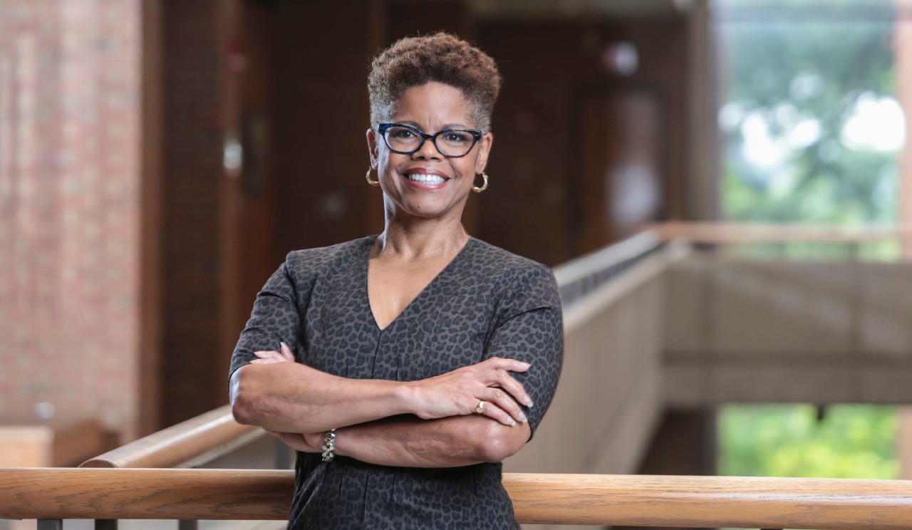 a woman stands with her arms folded and smiling
