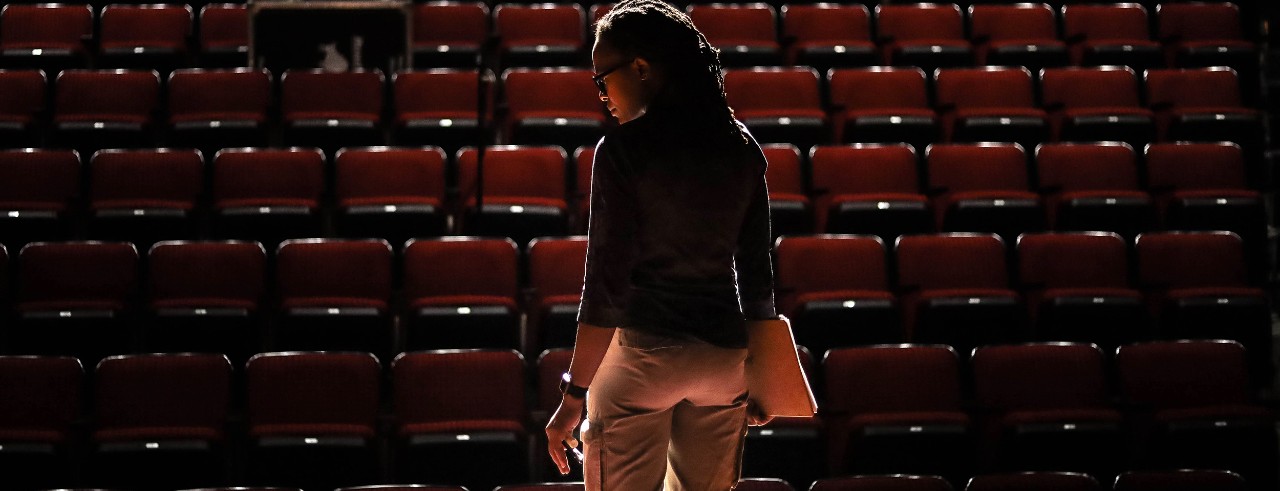 Rachael Blackwell stands on a stage in dramatic lighting