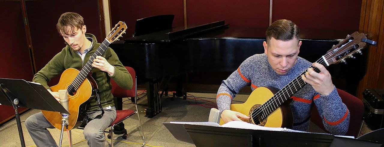 Two students play guitar in a recording studio
