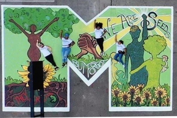 A large letter M is filled with colorful figures to represent hope in Cincinnati's Black Lives Matter! street mural.