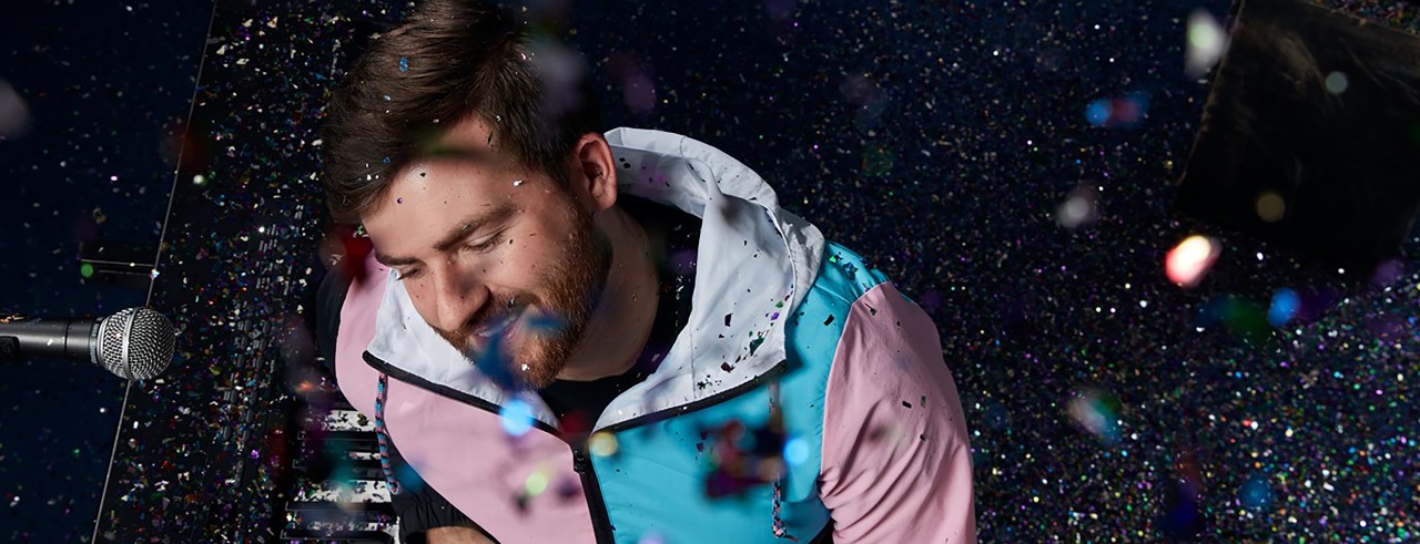 CCM alumnus Ryan Fine performs at the piano with confetti falling all around him