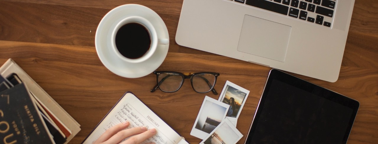 online learning set up with computer, cup of coffee, photos, journal