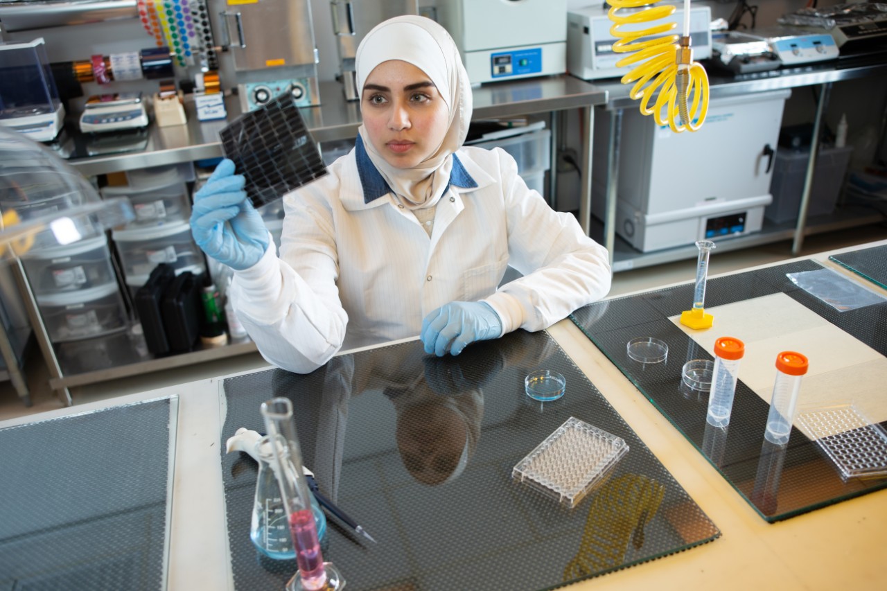 Engineering student in a lab looking at a slide