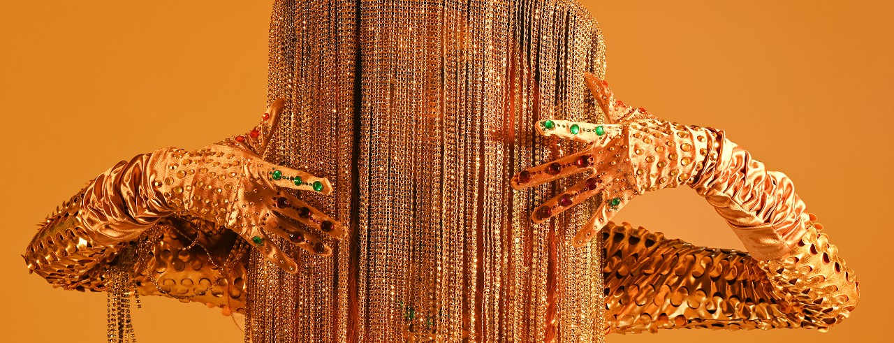 A performing artist posing against a yellow background