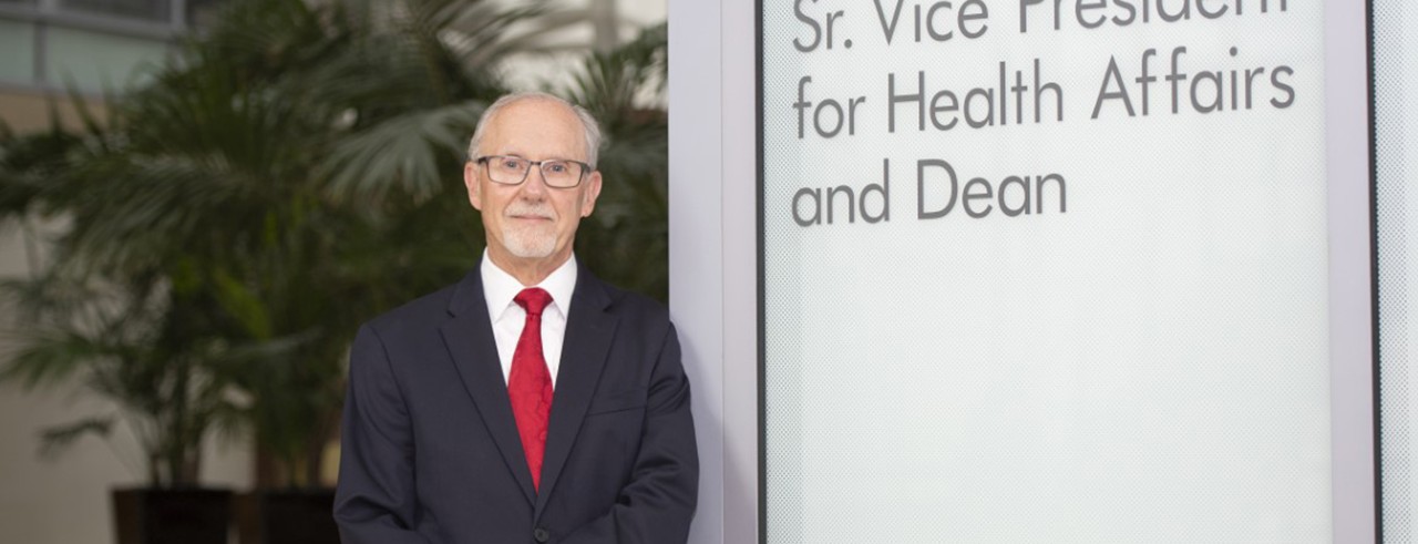man with red tie in front of dean sign