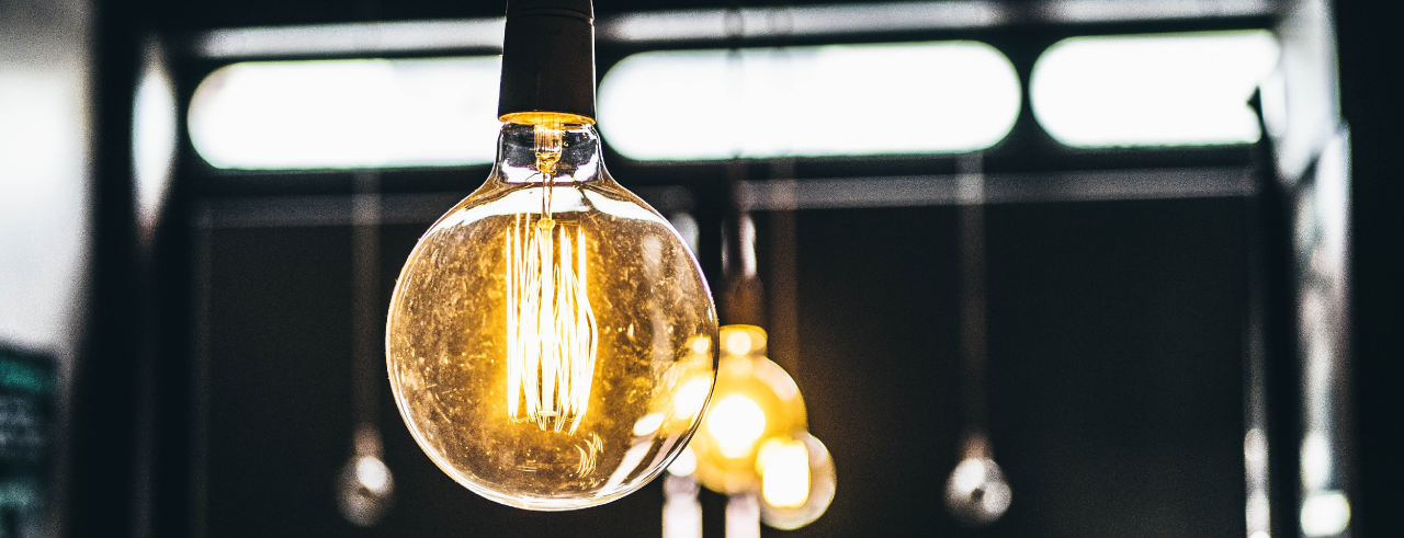 a round, lit lightbulb hanging from the top of the frame in the foreground, with other lights hanging in the background