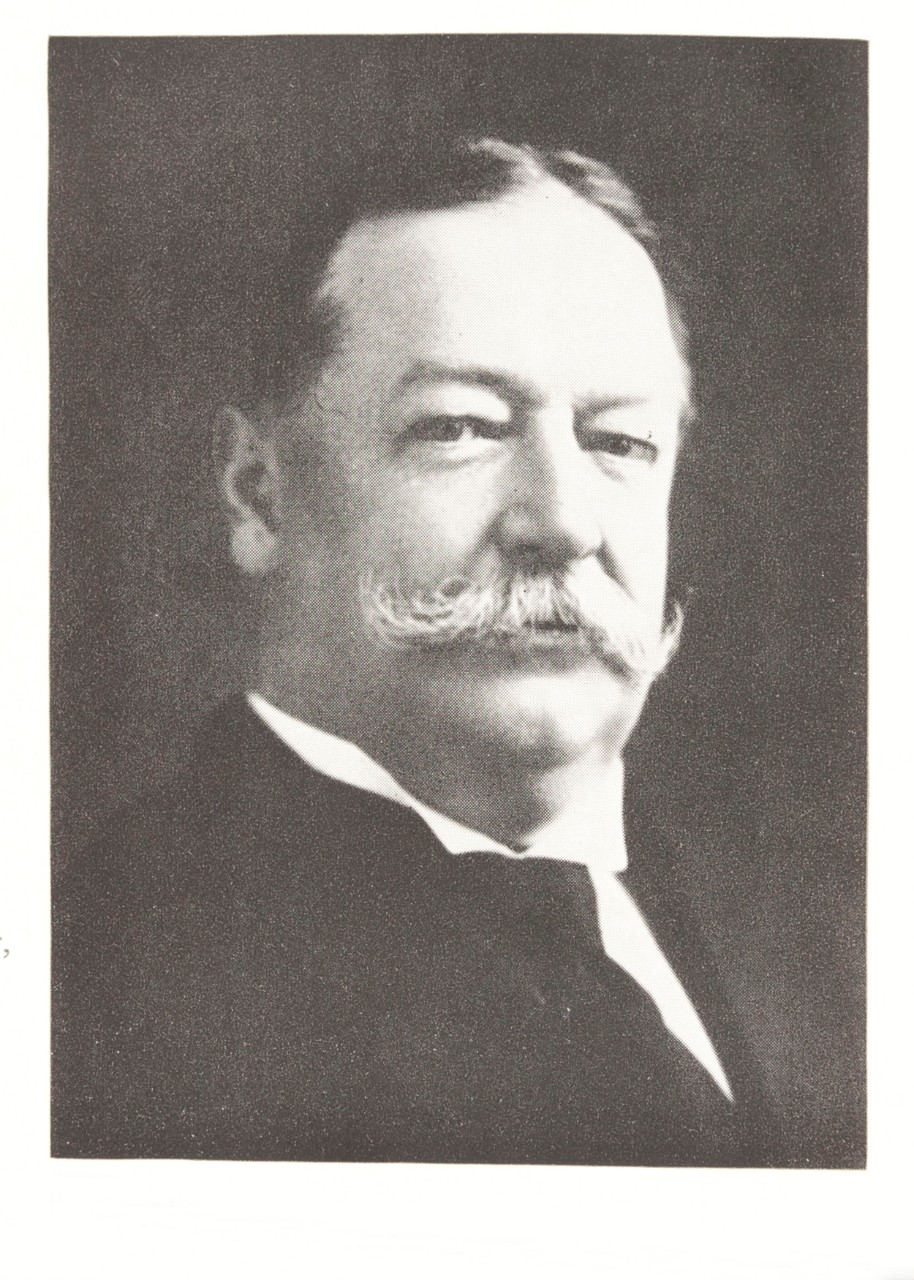 Black and white historical photo of a white man with handlebar mustache