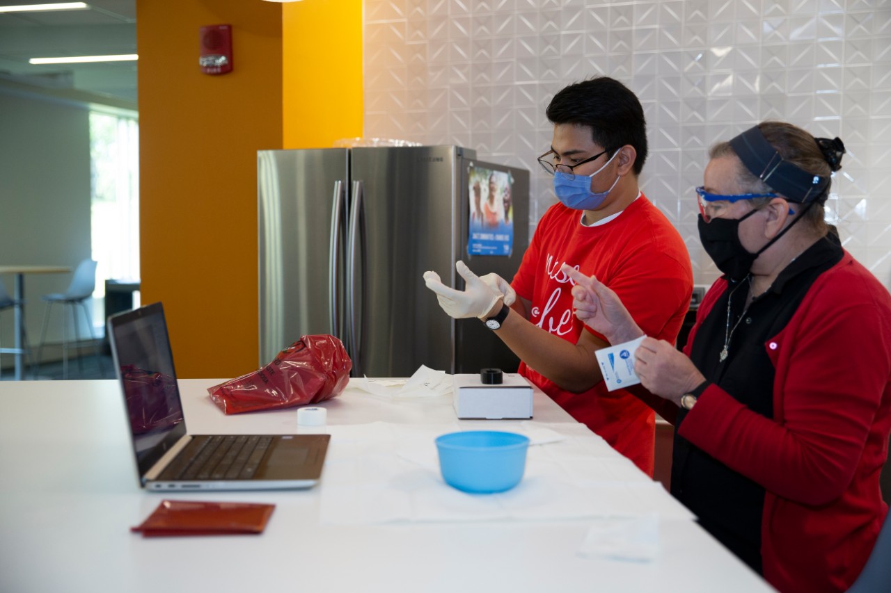 A nursing student receivers instruction from a professor on the use of a task trainer