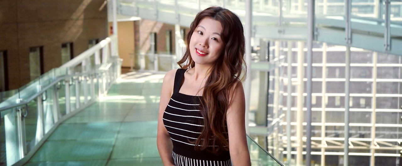 UC pharmacy PhD grad Tianyi Liu stands on UC's College of Medicine atrium bridge.