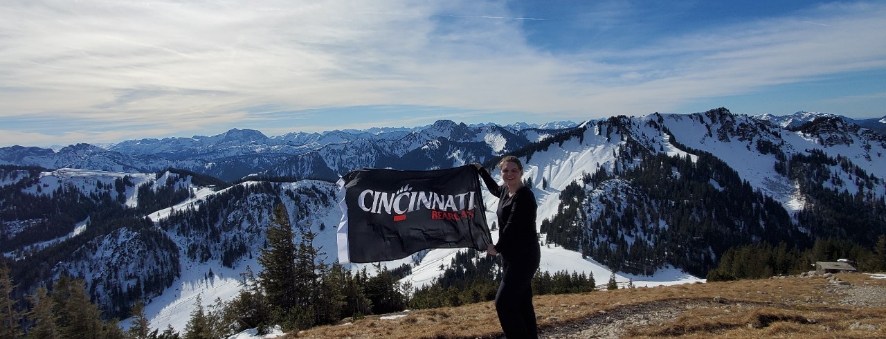 Nichole Criner holds UC flag in front of snow-capped mountains