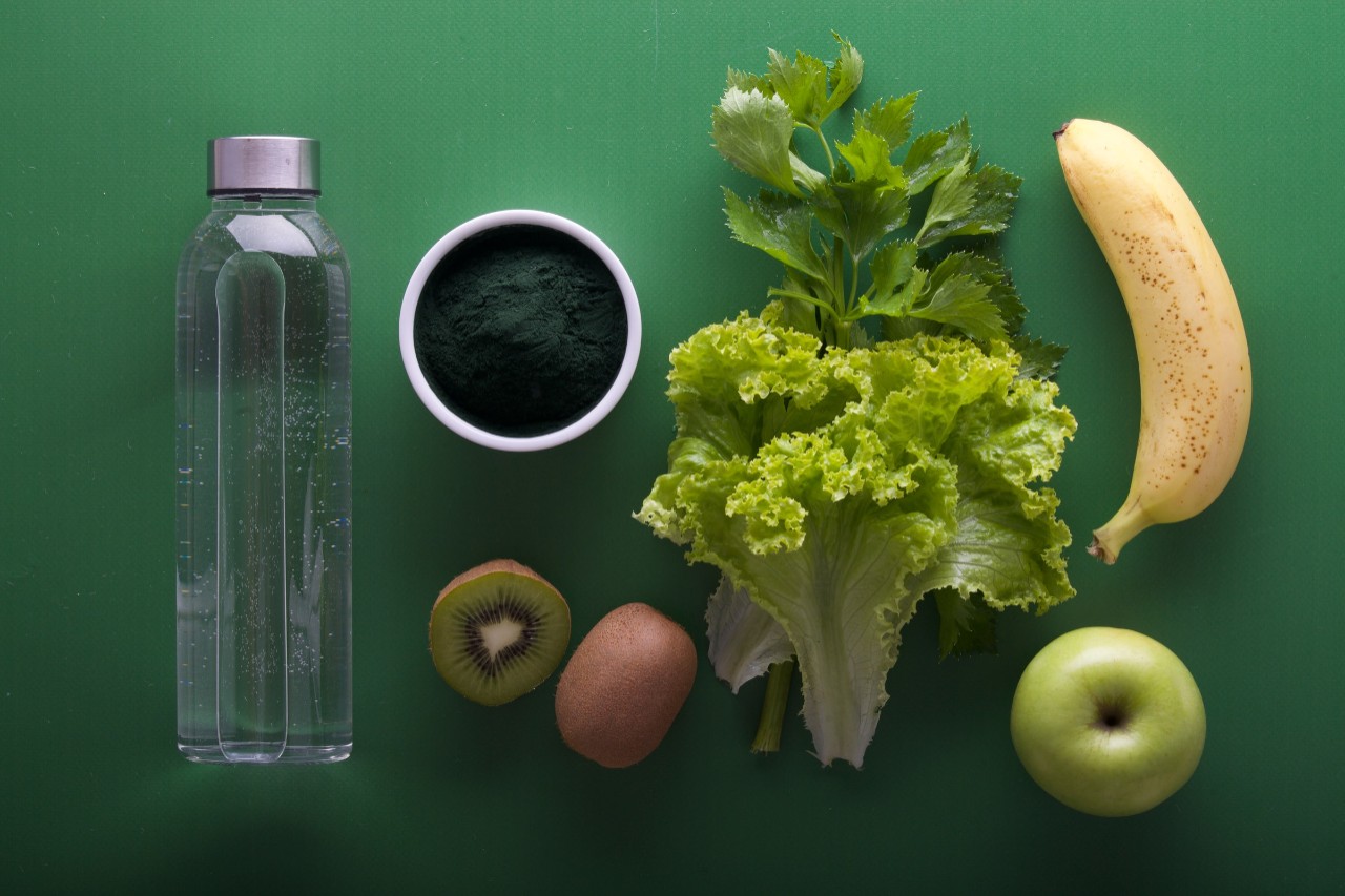 fruits and vegetables and water on a green table