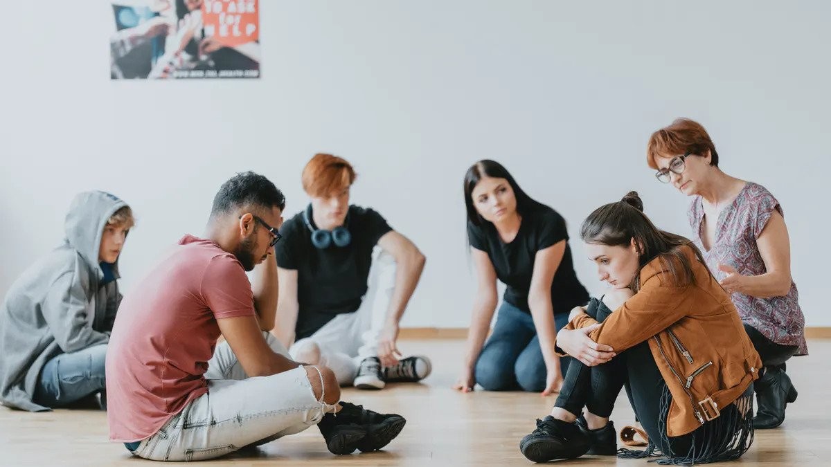 a group of young people seated on the floor in a circle 